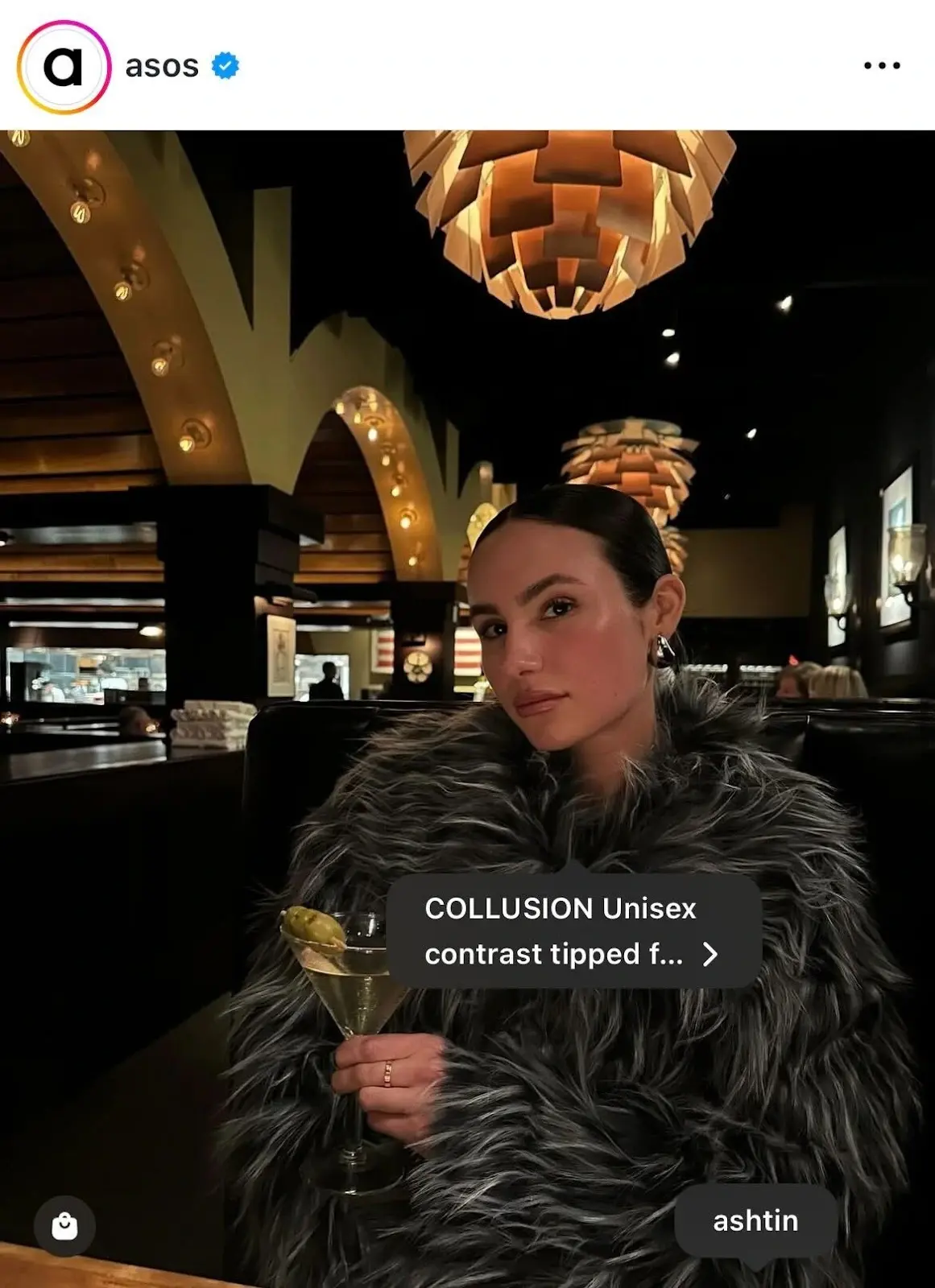 Screenshot from Instgram user asos of a woman in a faux fir coat drinking a martini in a bar.